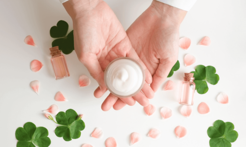Two hands surrounded by leaves hold a clean beauty product